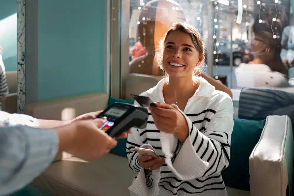 customer paying via contactless payment whilst holding her phone and smiling at the waiter