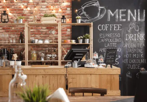 Independent café counter with chalkboard menu showing coffee options including espresso, cappuccino and latte.