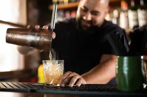 Male making cocktails in his bar, happy with his card machine for pubs and restaurants
