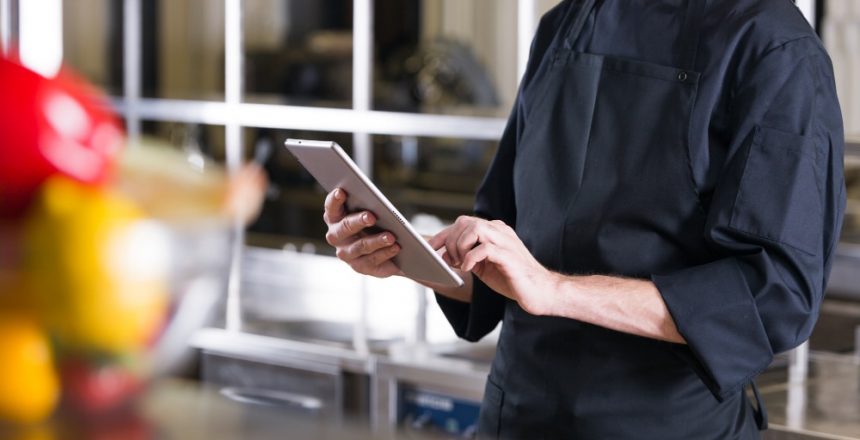 business owner using tablet whilst standing behind the bar.