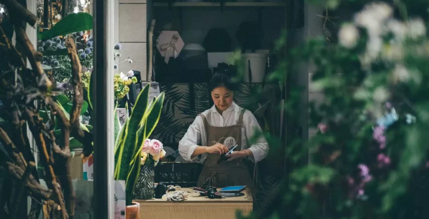 shop owner standing in shop using credit card machine